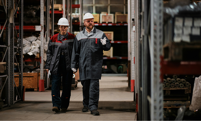 Two individuals walking through a factory.