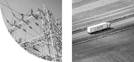 Electrical grid system and truck driving on a road that has farmland on both sides of it.